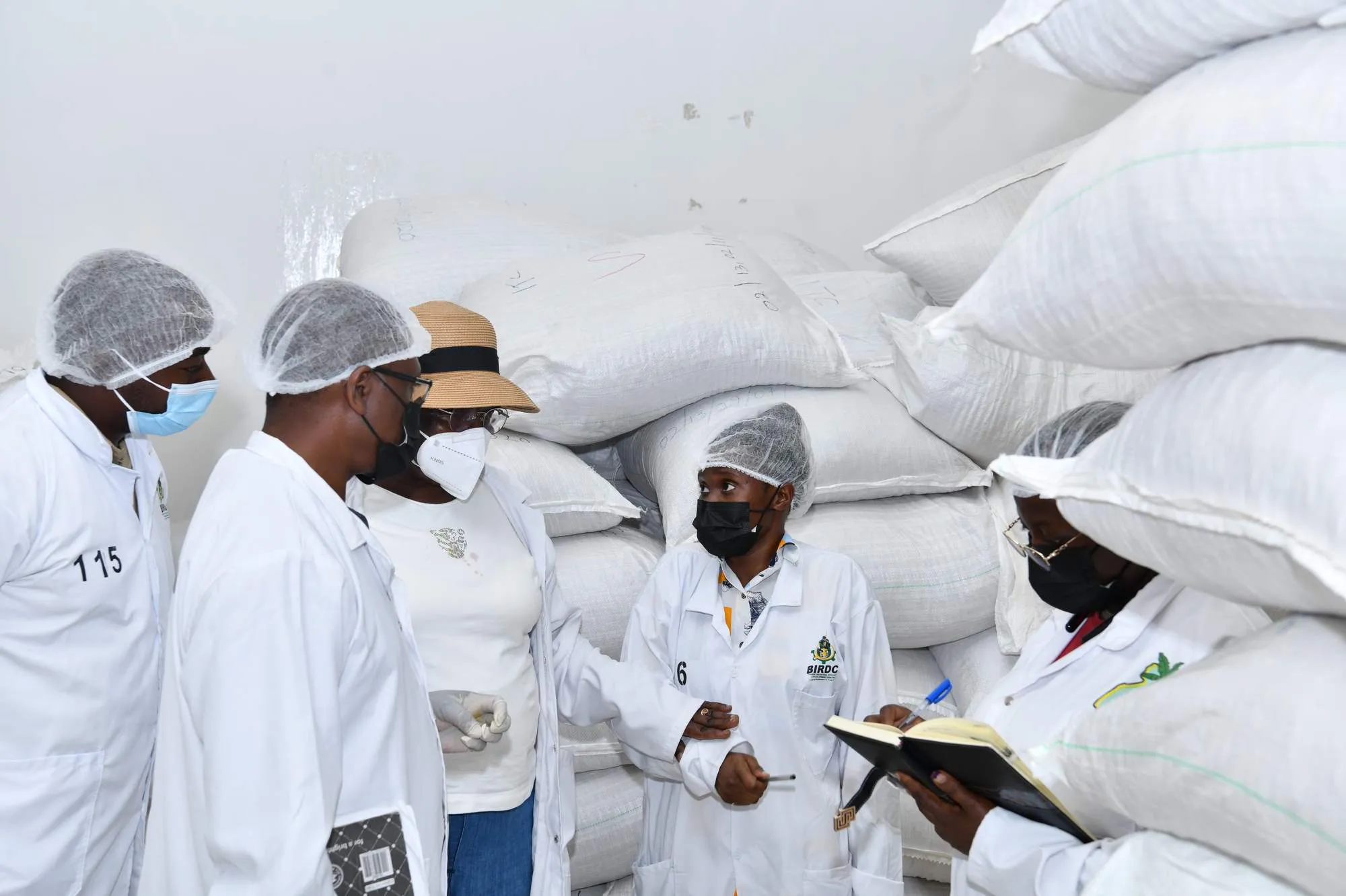 BIRDC staff in lab coats examining flour production in the Bushenyi factory storage area
